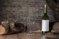 Close up of an empty glass surrounded by a bottle of wine and chunks of wood on a wooden table on an out of focus background.