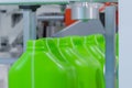 Empty green plastic jerry cans falling from conveyor belt at exhibition