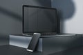 Close up of empty laptop and smartphone on dark gray desk. Concrete wall background, shadows and pedestal or podium. Device Royalty Free Stock Photo