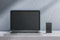 Close up of empty laptop and smartphone on gray desk. Concrete wall background. Device presentation and online education concept. Royalty Free Stock Photo