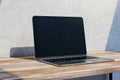 Close up of empty mock up laptop computer screen on wooden desktop and concrete wall background with shadow. Designer desktop and Royalty Free Stock Photo