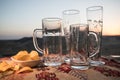Close up empty mugs of beer on a sunrise background with mountains. Beer party is over concept. Royalty Free Stock Photo