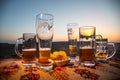 Close up empty mugs of beer on a sunrise background with mountains. Beer party is over concept. Royalty Free Stock Photo