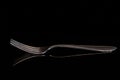 Close-up of an empty old fork with long tines reflected against a dark background Royalty Free Stock Photo