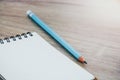 Close up empty open lined notebook and blue color pencil on wooden table background with copy space selective focus Royalty Free Stock Photo