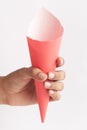 Close-up of empty pink white Paper cone bag holding in hand, for  snack packaging, craft paper for wrapping fries and nuggets in Royalty Free Stock Photo