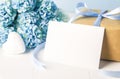 Close up of empty white greeting card  with brown recycle gift box and blue Hydrangea flowers on blue wooden background Royalty Free Stock Photo