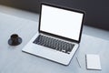 Close up of empty white laptop on concrete desktop with coffee cup, notepad, pen, mock up place on screen, blurry background. 3D Royalty Free Stock Photo