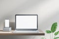 Empty white laptop and smartphone on designer office desktop. Decorative plant and concrete wall background. Mock up, Royalty Free Stock Photo