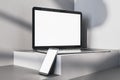 Close up of empty white laptop and smartphone on gray desk. Concrete wall background, shadows and pedestal or podium. Device Royalty Free Stock Photo