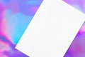 Close up of empty white rectangle poster mockup lying diagonally on holographic background