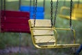 Close-up of empty wooden blue, yellow, vintage seats of multi-colored carousel hanging on chains. Royalty Free Stock Photo