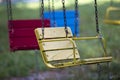 Close-up of empty wooden blue, yellow, vintage seats of multi-colored carousel hanging on chains. Royalty Free Stock Photo