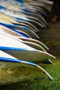 Close Up Of The End Of Blue And Silver Metal Canoes Lined Up In Grass For Rent
