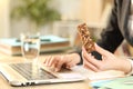 Entrepreneur hands holding snack bar working on laptop Royalty Free Stock Photo