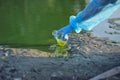 Close-up environmentalist hand of a researcher in a process of taking a sample of contaminated water from a lake