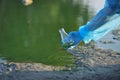 Close-up environmentalist hand of a researcher in a process of taking a sample of contaminated water from a lake