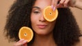 Close up ethnic model holding two slices of orange citrus posing beige background African American girl woman vitamin Royalty Free Stock Photo