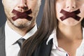 Close up of european man and businesswoman with taped mouthes.