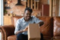 Close up excited African American man unpacking parcel at home Royalty Free Stock Photo