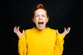 Close-up of excited angry young woman screaming with closed eyes on isolated black background.