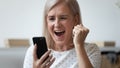 Close up excited older woman shouting, using phone, celebrating success