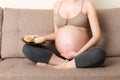Close up of excited pregnant woman is eating cakes with great pleasure relaxing at home. Enjoying sweet food during pregnancy Royalty Free Stock Photo