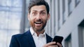 Close-up excited surprised man reading email notification on mobile phone getting good news happy satisfied emotional Royalty Free Stock Photo