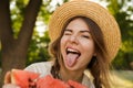 Close up of excited young girl in summer hat spending time at the park, showing slice of a watermelon Royalty Free Stock Photo