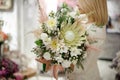 close-up of exclusive bouquet of different white flowers decorated with greenery in hands of woman