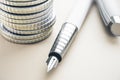 Close up of expensive classic pen and stacked silver coins on white desktop background. Finance and accounting concept. 3D