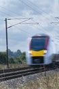 Close up of an express train with overhead electrification speeding through English countryside with motion blur Royalty Free Stock Photo