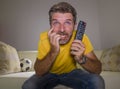 Close up expressive portrait young excited and nervous football supporter man watching soccer game on television at living room Royalty Free Stock Photo