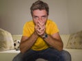 Close up expressive portrait young excited and nervous football supporter man watching soccer game on television at living room Royalty Free Stock Photo