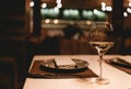 Close up of exquisite glass of champagne stands on table in restaurant, next to empty plate with cutlery and napkin. White wine on Royalty Free Stock Photo