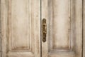 Close up exterior view of an ancient wooden garage door. Metallic elements, handle and keyhole are visible. White and grey painted Royalty Free Stock Photo