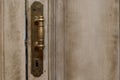 Close up exterior view of an ancient wooden garage door. Metallic elements, handle and keyhole are visible. White and grey painted