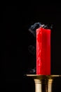 Close-up of extinguished red candle with smoke, in golden candlestick, black background Royalty Free Stock Photo