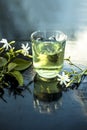 Close up of extract of Indian jasmine flower or juhi or Jasminum Auriculatum on wooden surface in a transparent glass with raw flo