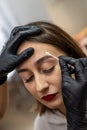 Close-up of an eyebrow designer correcting and touching up eyebrows. Royalty Free Stock Photo