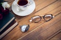 Close up of eyeglasses by stopwatch and tea with books