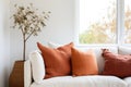 Close up of fabric sofa with terra cotta pillow against window and white wall. Scandinavian home interior design of modern room. Royalty Free Stock Photo