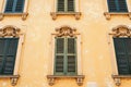 A close-up of the facade of an old yellow building with stucco windows and closed shutters. Royalty Free Stock Photo
