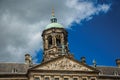 Close-up of facade with sculptures and dome with golden clock in the Royal Palace of Amsterdam.