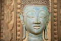 Close up of a face of an ancient copper Buddha statue outside of the Hor Phra Keo temple in Vientiane, Laos.