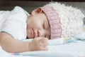 Close up face of baby sleeping on clothes bed wearing wool hood Royalty Free Stock Photo