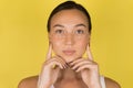 Close-up face of beautiful woman with anti-aging and wrinkle eye contour cream. Yellow background Royalty Free Stock Photo