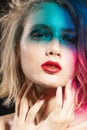 Close-up face of a beautiful young blonde girl with red lips and her face is covered with colored shadows from multi colored Royalty Free Stock Photo