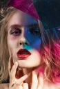 Close-up face of a beautiful young blonde girl with red lips and her face is covered with colored shadows from multi colored Royalty Free Stock Photo