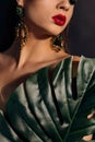 Close up face of beautiful young woman covering by green monstera green palm. Portrait of beauty woman with makeup red lips clear Royalty Free Stock Photo